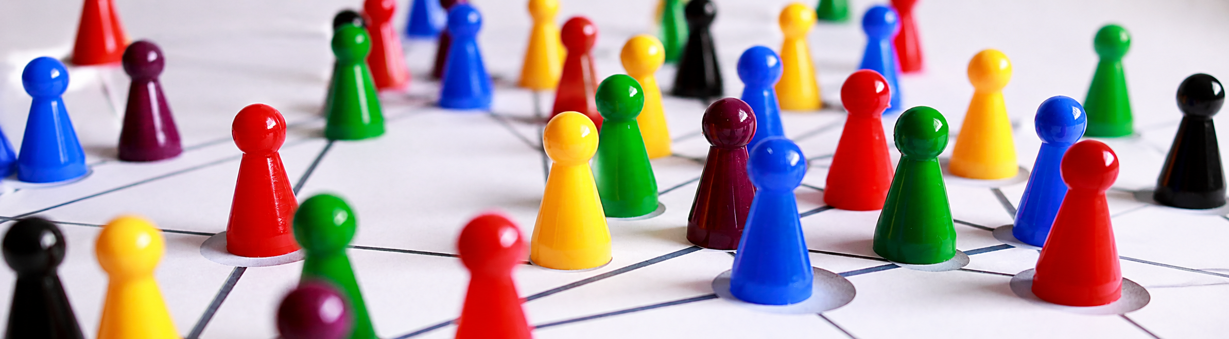 Pedine da gioco colorate disposte su una rete di nodi interconnessi, a rappresentare relazioni e capitale sociale.